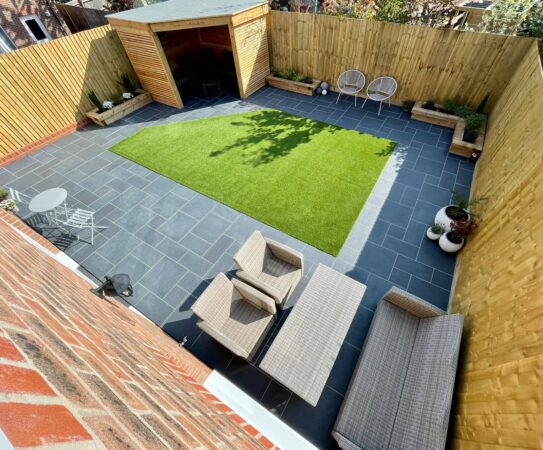 Compact courtyard garden with artificial lawn, paving and planted borders