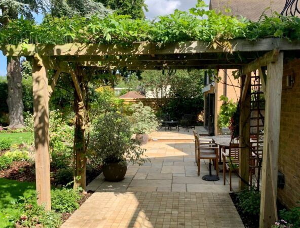 Timber pergola and paved walkway through a mature garden